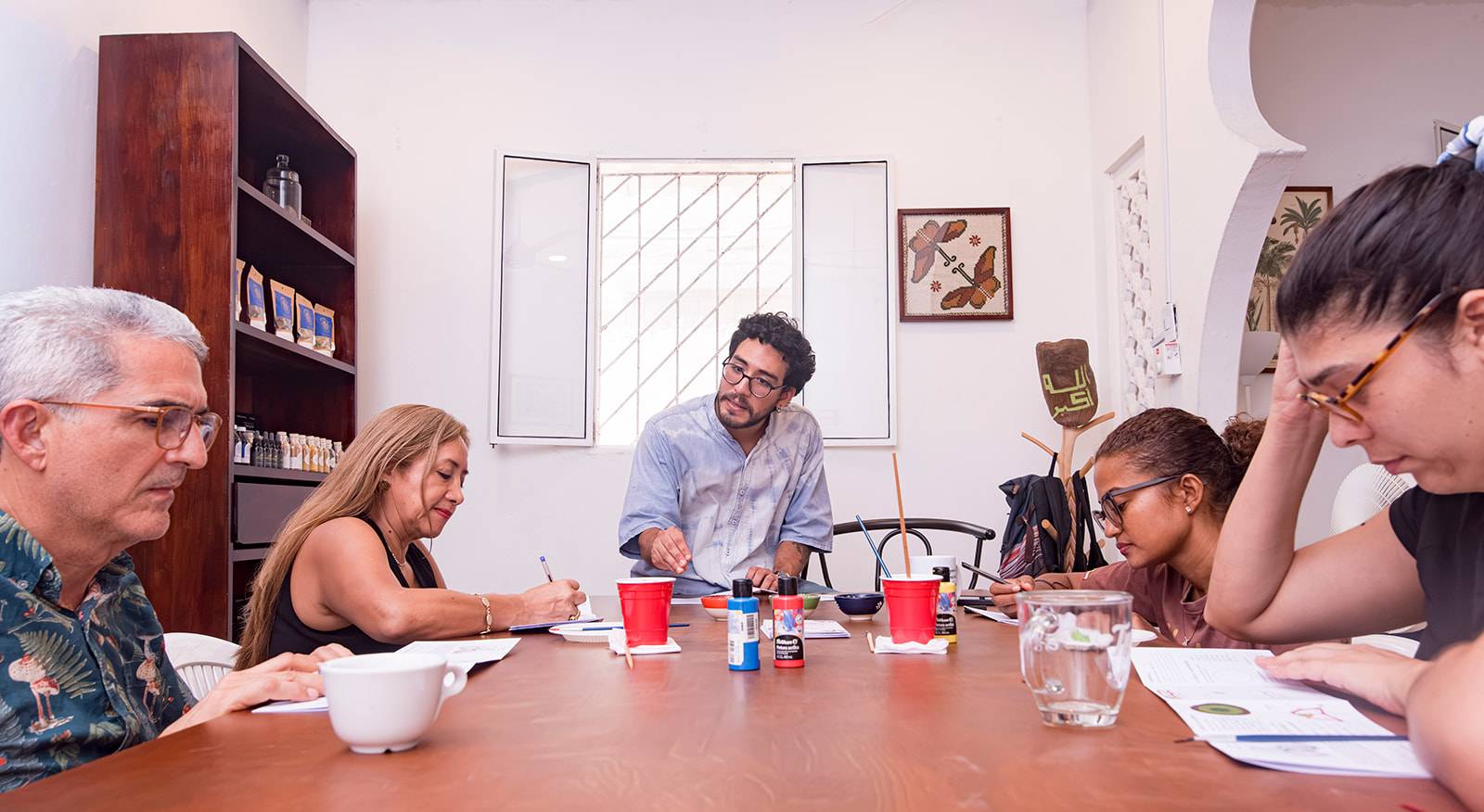 Participantes tomando notas alrededor de la mesa junto al guía